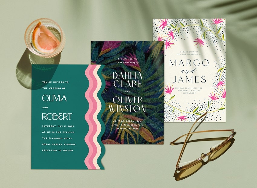 3 tropical wedding invitations and a pair of sunglasses on a table