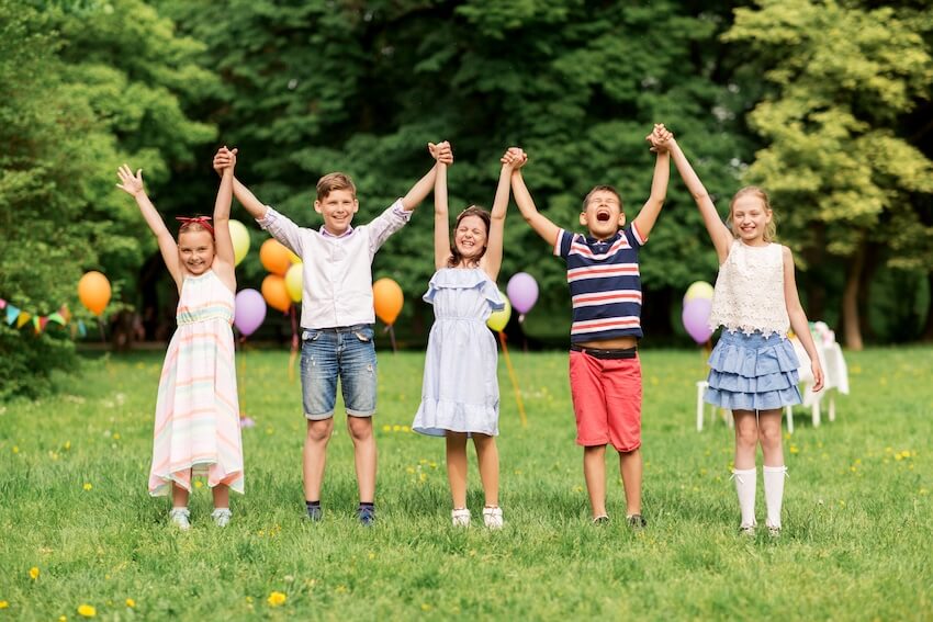 5 kids happily holding hands while raising their arms