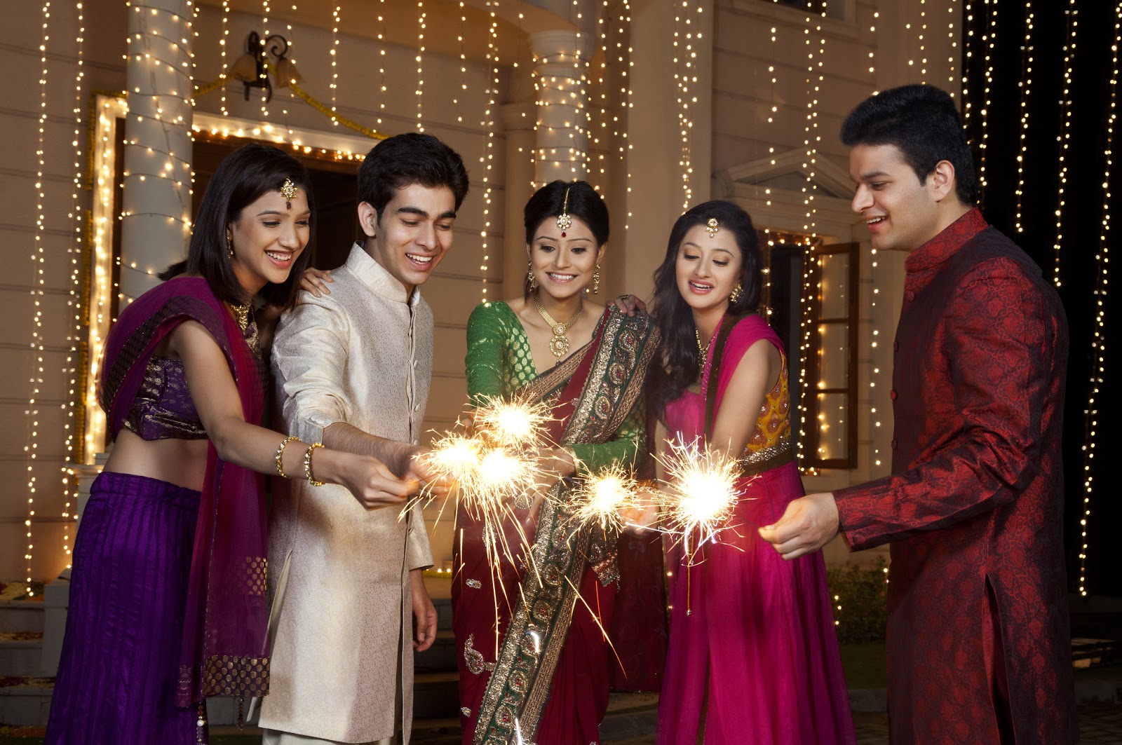Diwali party ideas: A group of guests in traditional saris, hold sparklers