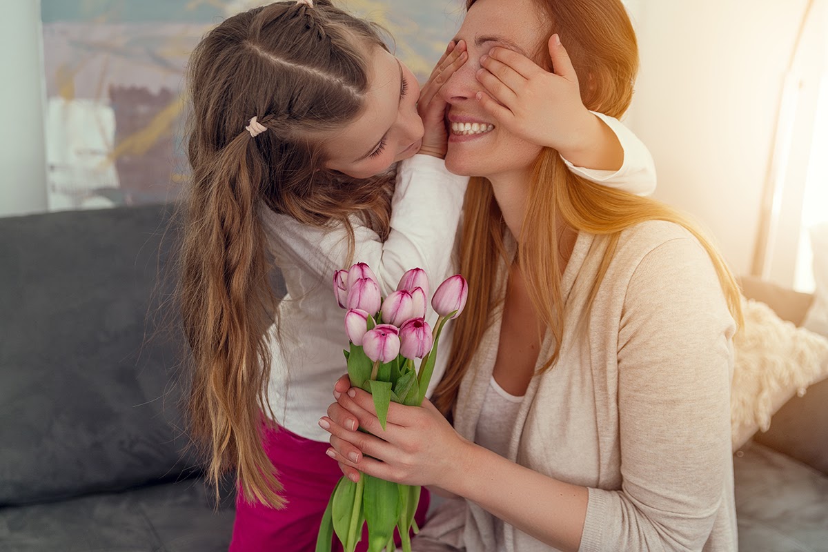 Mom holds tulips as daughter covers mom's eyes