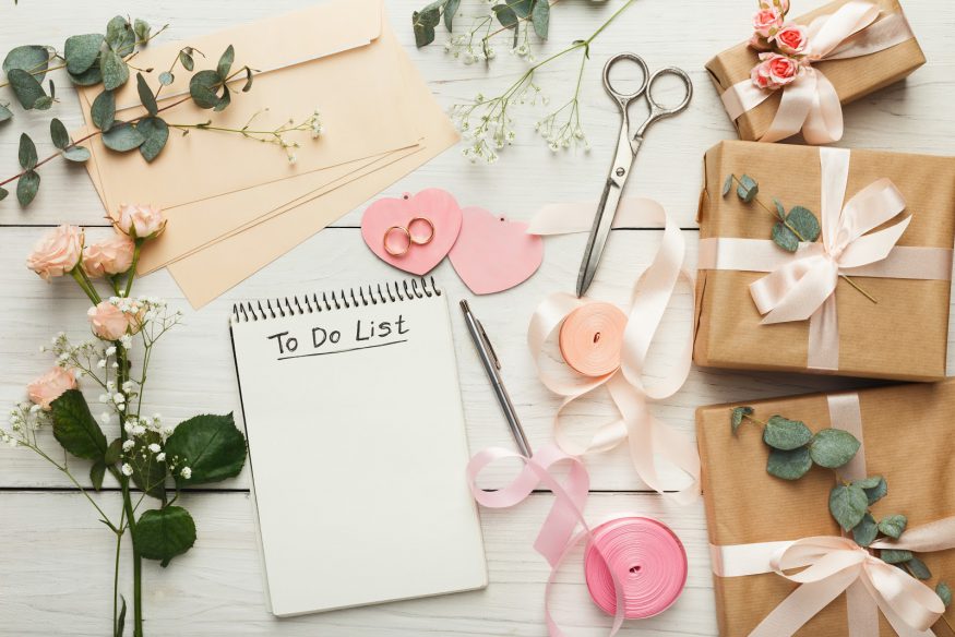 Party planning: a to-do list surrounded by fits, ribbon, envelopes, and flowers