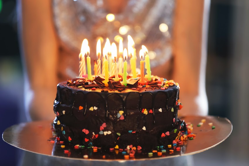 A woman carrying out a birthday cake with candles