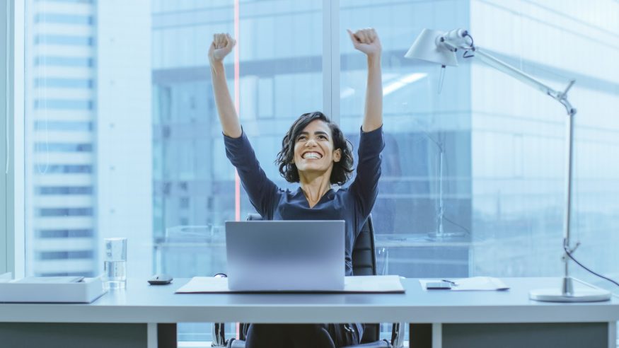 A business woman celebrates at her desk