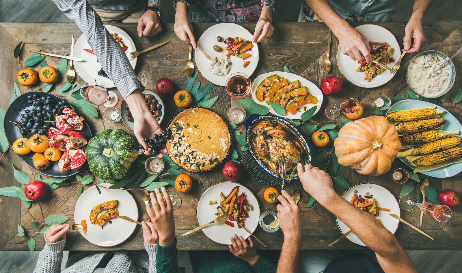 Hands reach across a Thanksgiving table for food