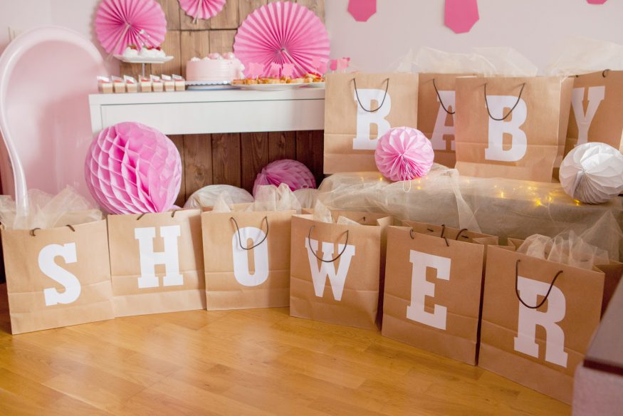 Baby shower ideas: A table of cupcakes behind gift bags that spell out "BABY SHOWER"