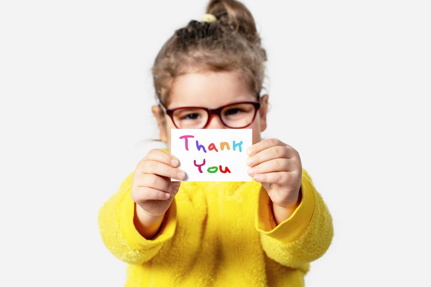 Thank you card ideas: A little girl holds up a handmade thank you card