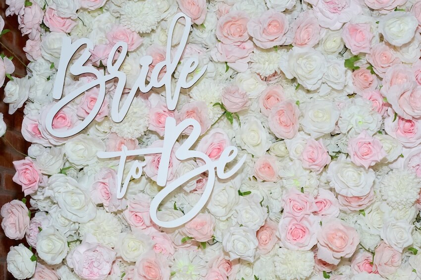 Who pays for bridal shower: Bride To Be lettering on top of pink and white flowers