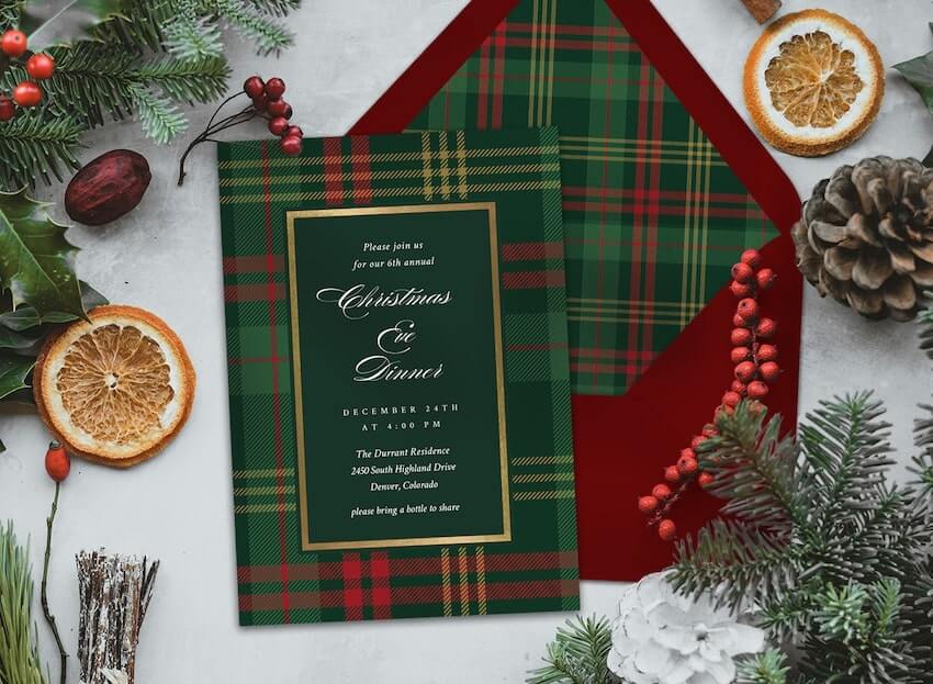 Christmas Eve invitation surrounded by dried orange slices, pine branches, pine cones, and red berries