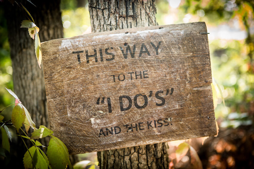 Budget rustic wedding ideas: THIS WAY TO THE I DO'S AND THE KISS signage