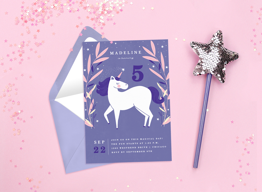 Unicorn invitations surrounded by pink glitter and a fairy wand