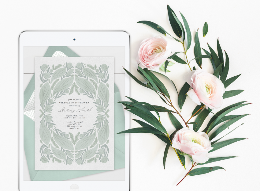 Virtual baby shower invitation on an iPad with florals laying next to it