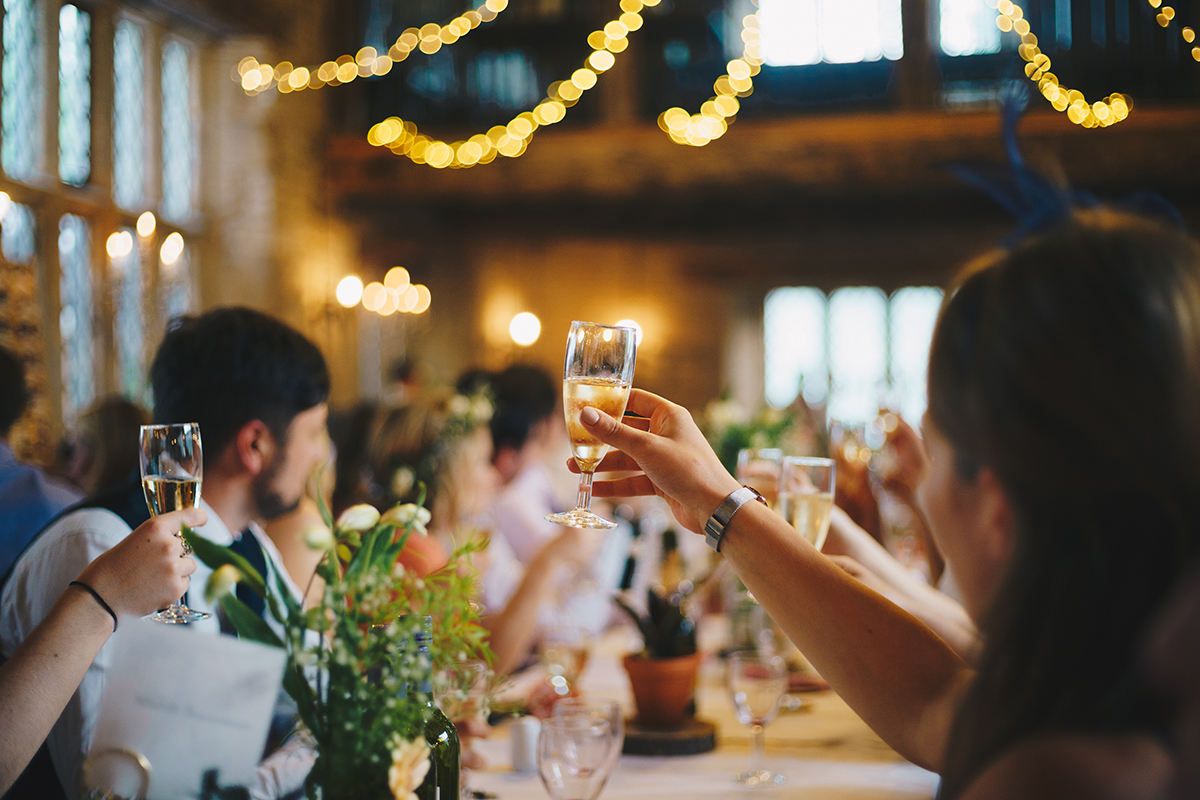 When to send wedding invitations: Guest's hold up their glasses to cheers at a wedding reception