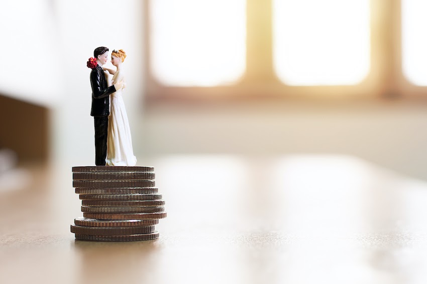 Average cost of wedding invitations: A bride and groom figurine stands on top of a stack of quarters