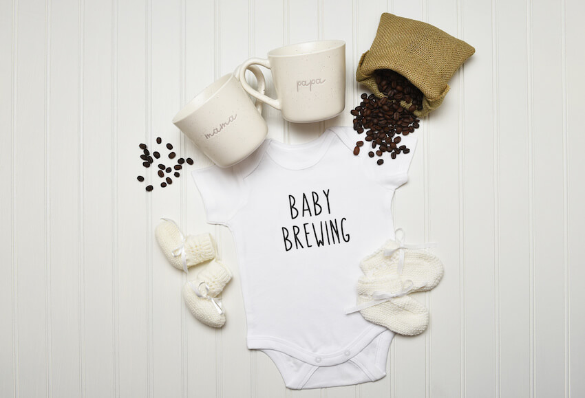 Fall pregnancy announcement: baby clothes, coffee cups, and coffee beans