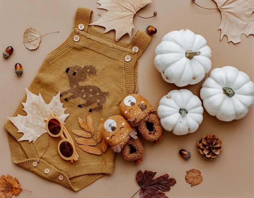 Baby clothes, pumpkins, a pair of baby shoes, and a pair of sunglasses