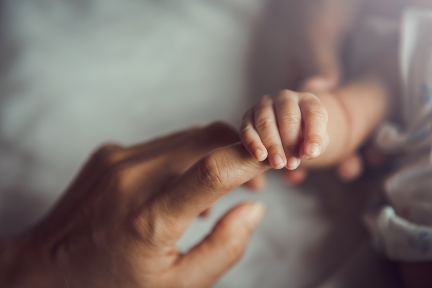 Newborn baby holding a mother's finger