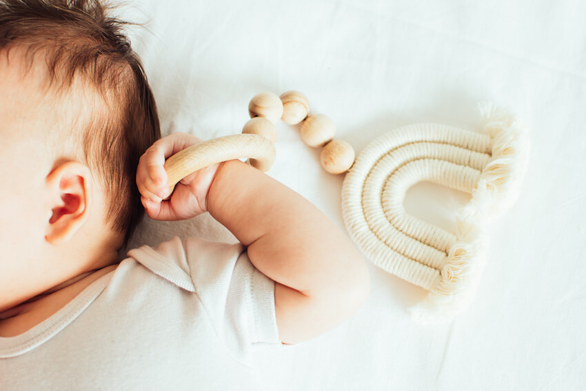 Rainbow baby shower: baby holding a wooden toy