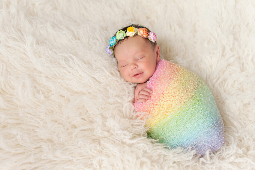 Rainbow baby announcement: baby wearing a rainbow colored swaddle