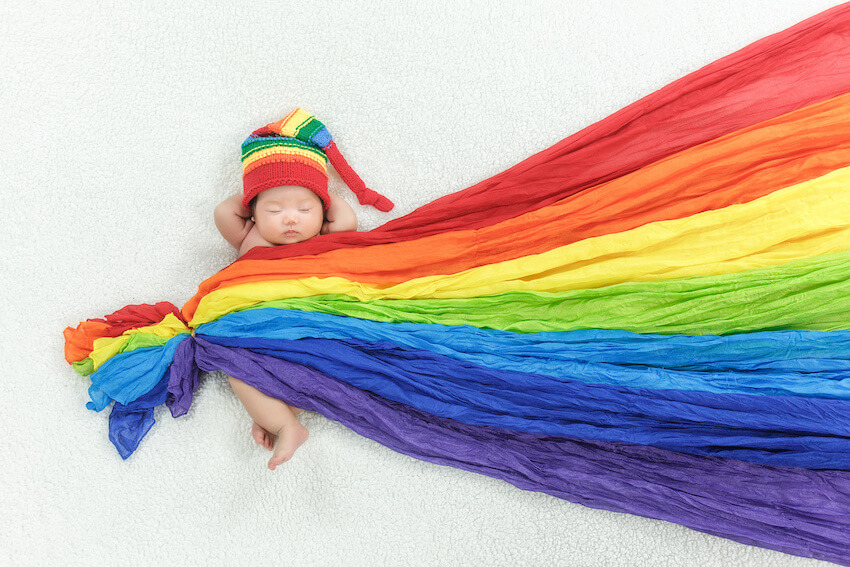 Rainbow baby shower: baby wearing a rainbow hat and rainbow blanket