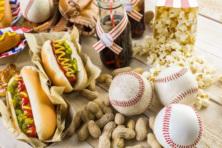 Baseball birthday party: baseball balls, peanuts, popcorn, hotdogs, and drinks on a table