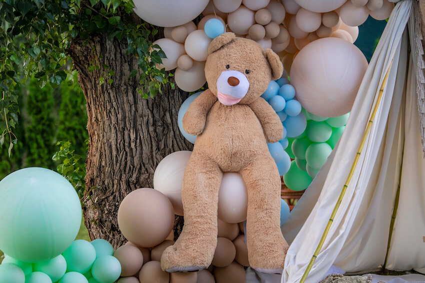 We can bearly wait baby shower: big brown teddy bear and colorful balloons