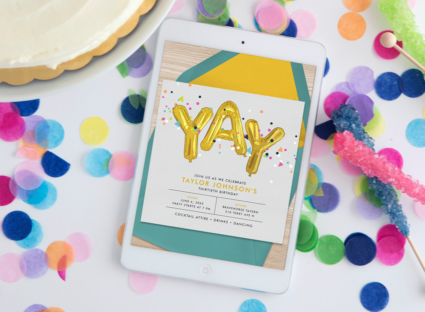 A tablet displaying a digital birthday invitation, surrounded by confetti, rock candy, and cake