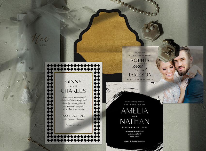 Black and white wedding invitations, a pair of earrings, and 2 rings