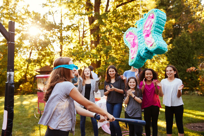 12 year old birthday party ideas: blindfolded teenager trying to hit a piñata