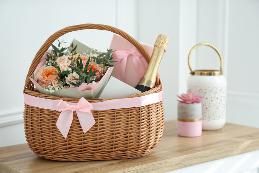 Wedding gift etiquette: bouquet of flowers and a bottle of wine in a basket