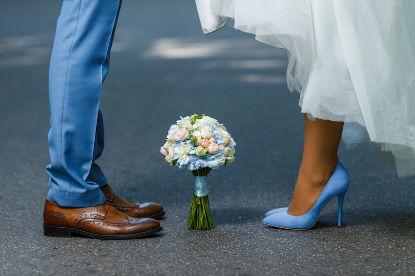 Blue wedding: bouquet of flowers placed between a bride and a groom