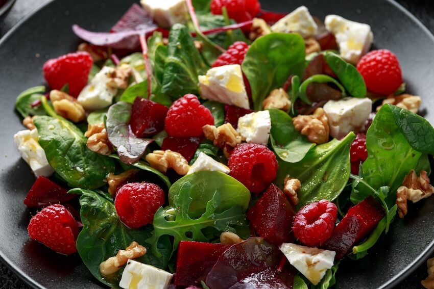 Summer dinner party ideas: bowl of salad with raspberries, walnuts, and feta cheese