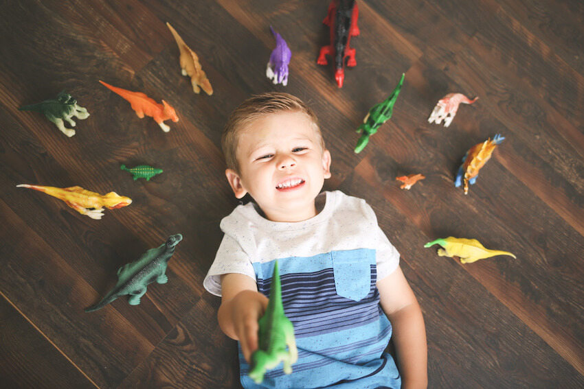 Dinosaur decorations: boy lying on the floor with dinosaur toys surrounding him