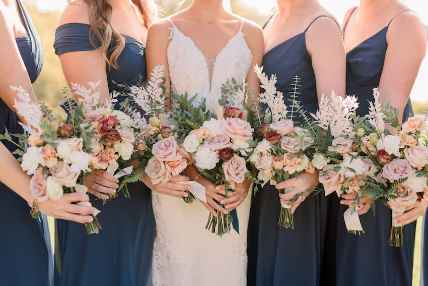 Navy blue wedding: bride and bridesmaids holding bouquets of flowers