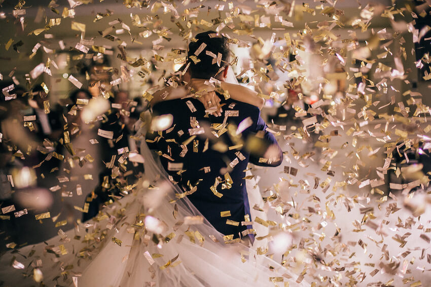 Bride and groom dancing while gold confetti falls around them