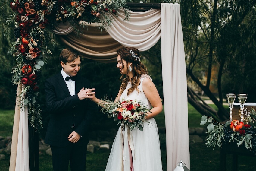 Fall colors for wedding: bride and groom exchanging rings at their wedding