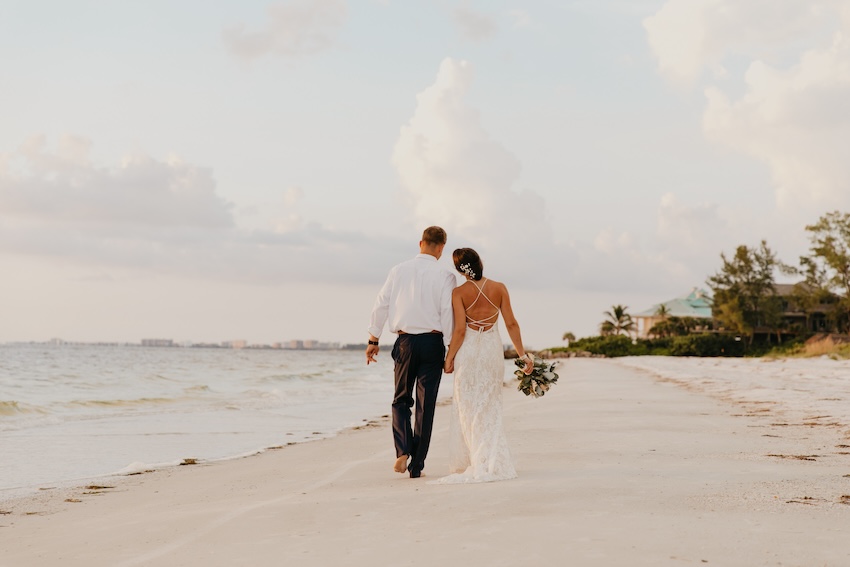 Destination wedding ideas: bride and groom walking at a beach