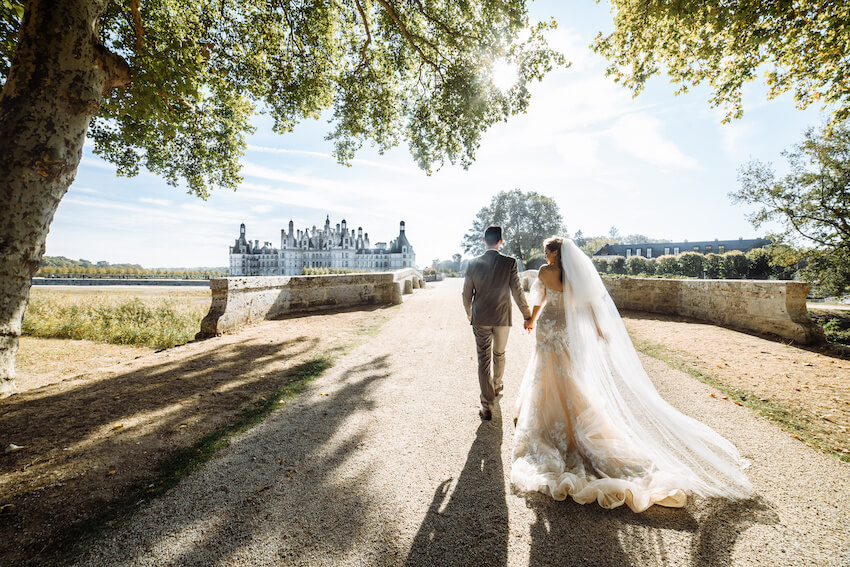 Fairytale wedding theme: bride and groom holding hands while walking outside