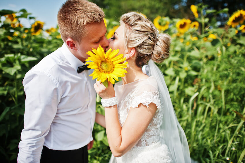 Sunflower wedding: bride and groom kissing in a field