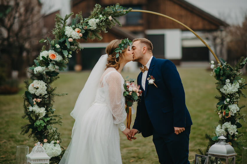 Bride and groom kissing under a floral arch