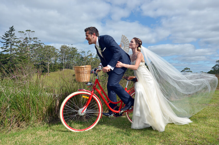 Whimsical wedding themes: bride and groom riding a bike