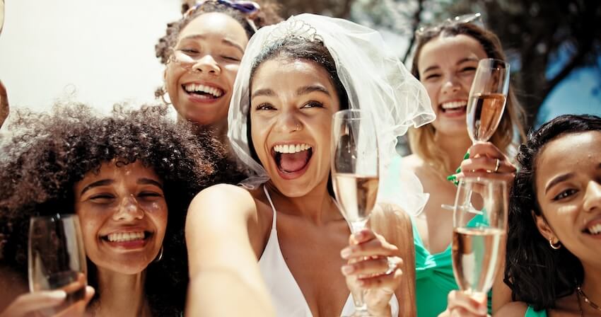 Summer bridal shower themes: bride and guests holding champagne glasses, smiling for a groufie