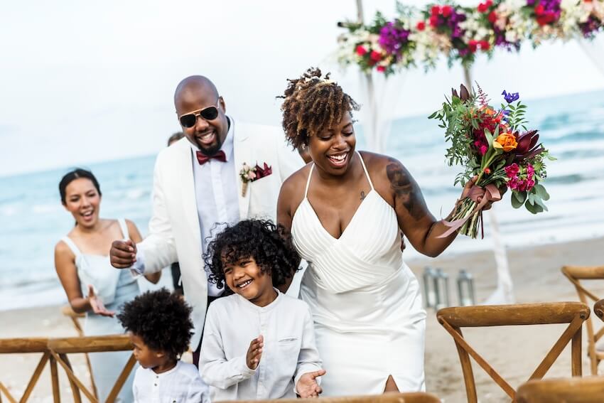 Destination wedding save the date: bride, groom, and their kids at a beach