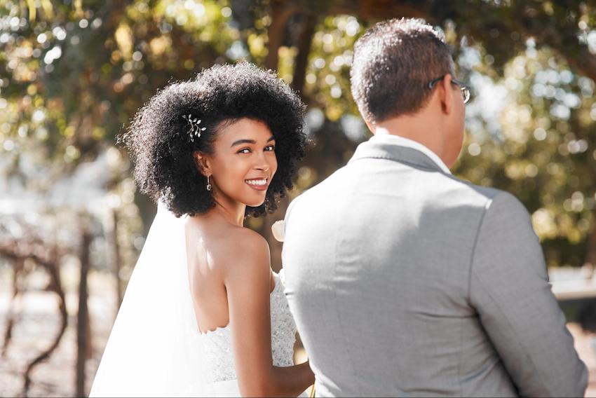 Songs to walk down the aisle to: bride looking at a camera while standing beside her groom