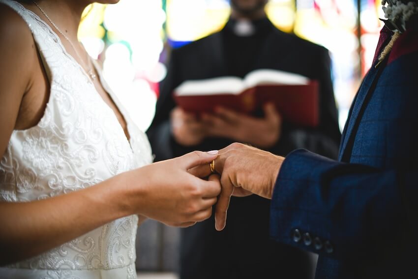 Traditional wedding vows: bride putting a ring on a groom’s finger