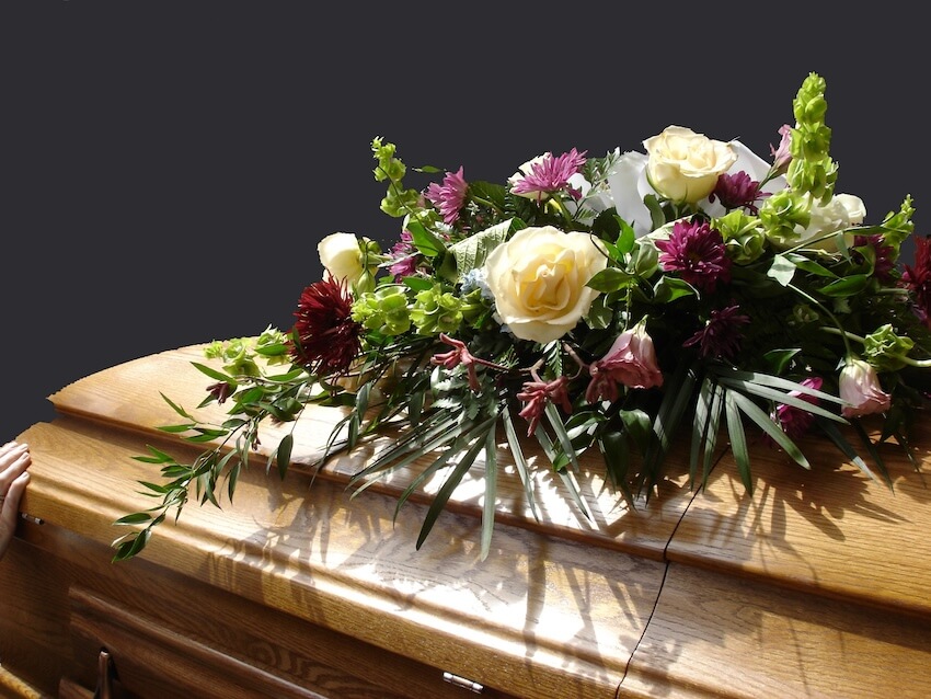 Celebration of life ideas: brown casket with flowers on top of it