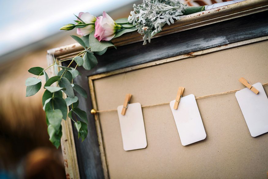 wedding guest list: cards pinned on a board using wooden clothespins