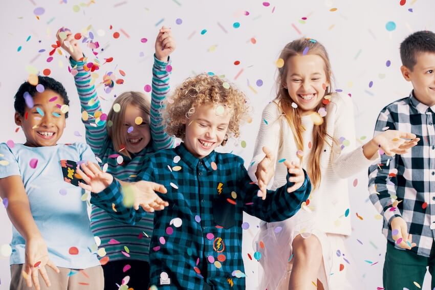 Tween birthday party ideas: children throwing colorful confetti up into the air
