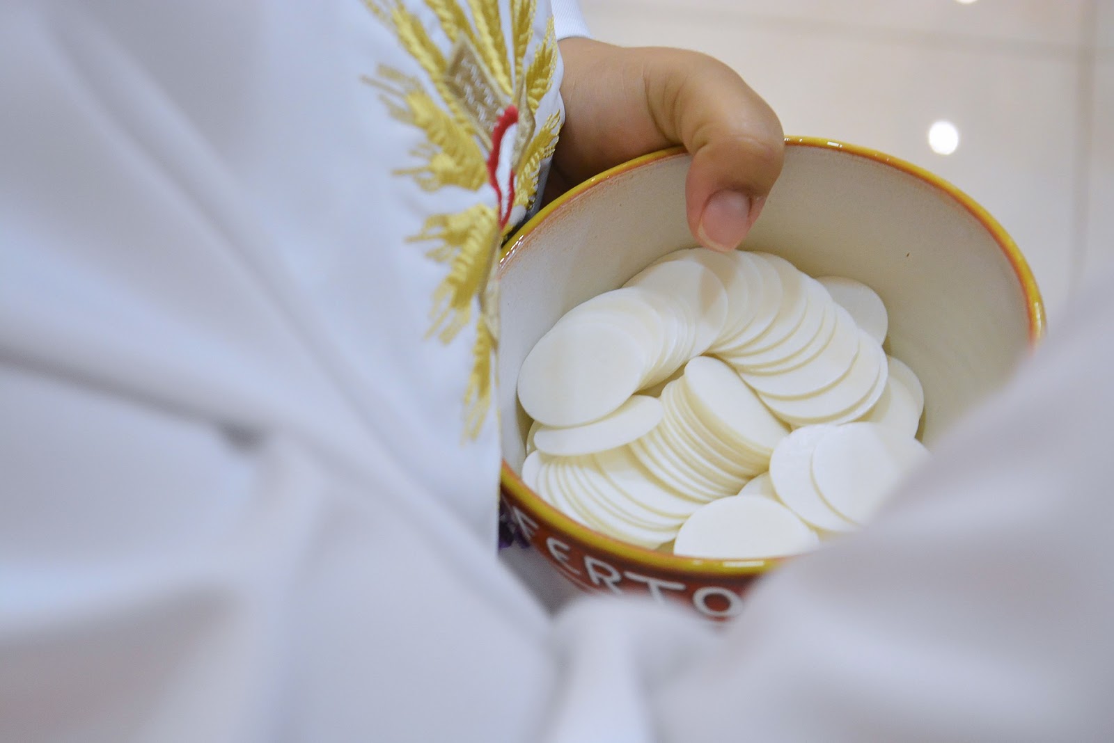 A robed person holds communion wafers