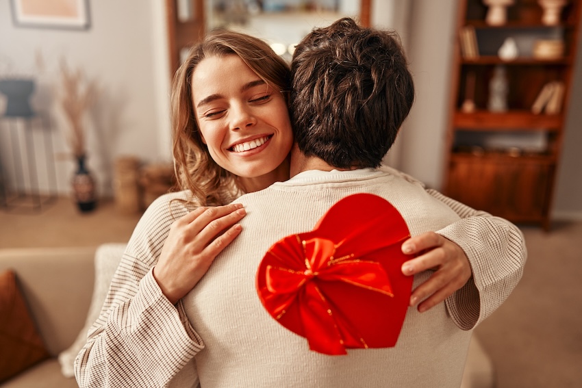 Anniversary gifts for her: woman hugging her husband while holding a gift