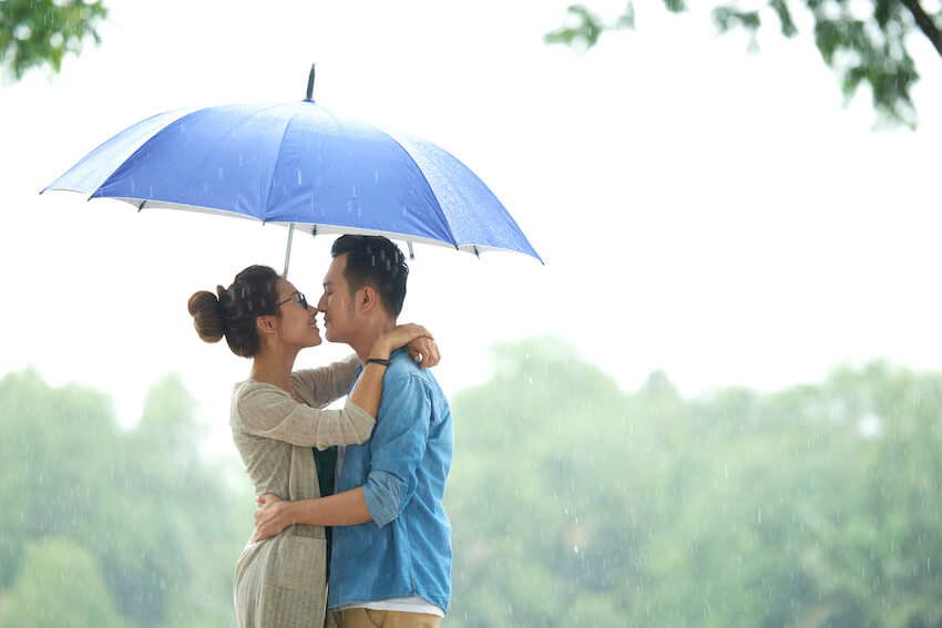 Romantic happy Valentines Day: couple holding an umbrella while hugging each other